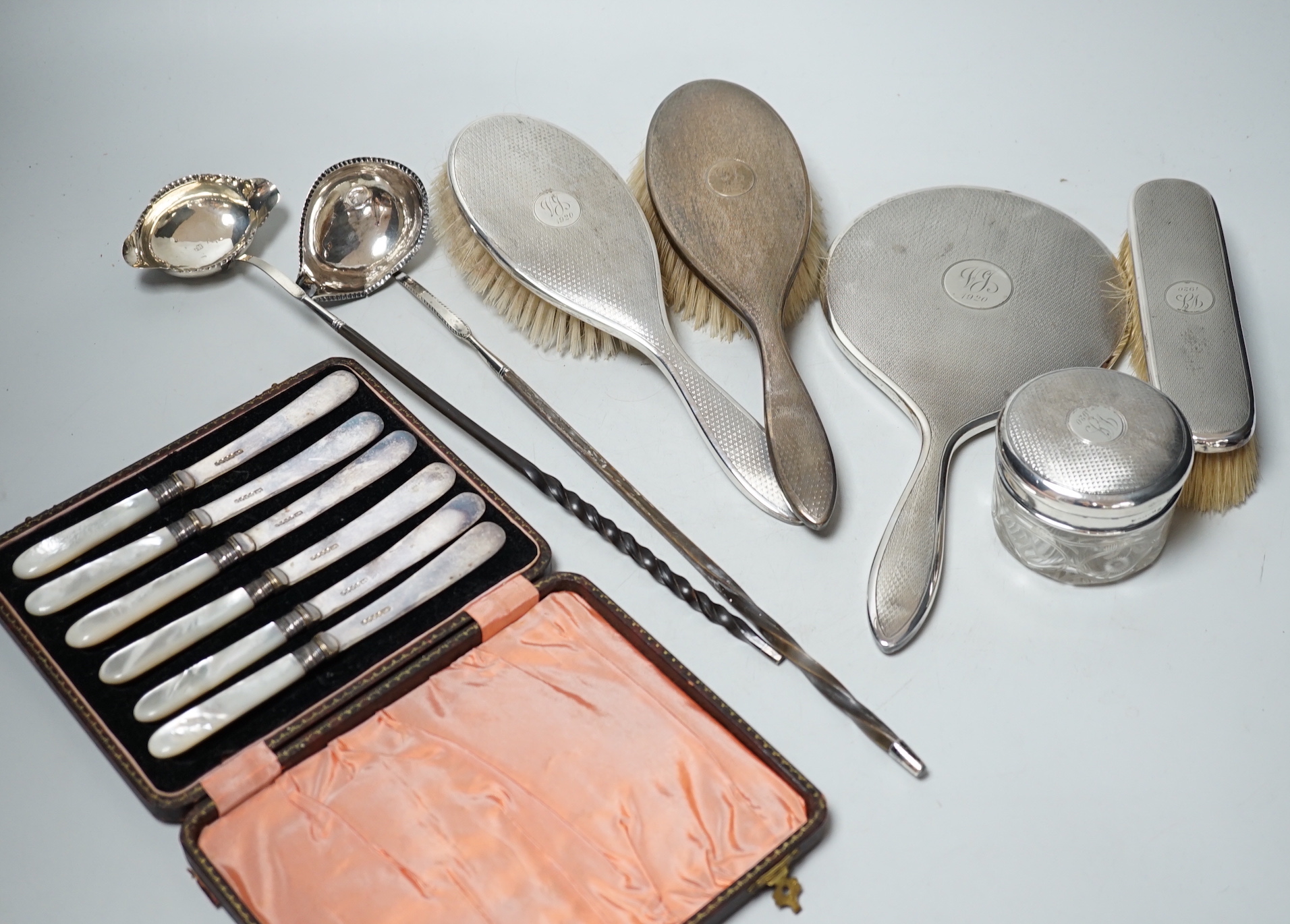 A George V silver mounted five piece dressing table set, two Georgian silver punch ladles and cased tea knives.